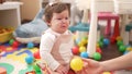 Adorable toddler sitting on floor looking ball crying at kindergarten