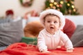 Adorable toddler wearing christmas hat lying on sofa at home