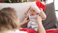 Adorable toddler wearing christmas hat sitting on sofa at home