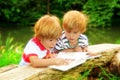 Adorable Twin Brothers Reading A Book Near The Lake At Summer