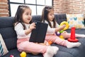 Adorable twin girls playing with hoops game using touchpad at home Royalty Free Stock Photo