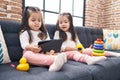 Adorable twin girls playing with hoops game using touchpad at home Royalty Free Stock Photo