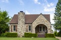 Adorable vintage rock home with rustic wood shutters and arched porch with porch swing- curb appeal