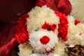 Adorable white and red Valentine stuffed puppydog with red fur around one eye and a valentine in its mouth