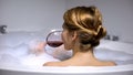 Adorable woman drinking wine in bath with foam bubbles, wellness and spa, relax