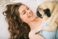 Adorable woman hugging her pug dog in bed Royalty Free Stock Photo