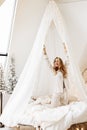 Adorable woman sit on canopy bed, smiling, stretching, gorgeous lady relaxing, spend winter holidays at home, enjoy Royalty Free Stock Photo