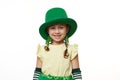 Adorable funny Leprechaun girl in green carnival hat, smiling looking at camera over white background. St Patrick's