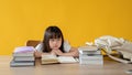 An adorable young Asian girl sitting at her study table with a bored face, doesn't want to study