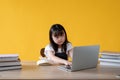 An adorable young Asian girl using a laptop studies an online lesson at her study table Royalty Free Stock Photo