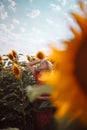 Adorable young caucasian girl posing in a sunflower field in the sun light. Woman in red summer style dress with open Royalty Free Stock Photo