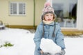 Adorable young girl building a snowman in the backyard. Cute child playing in a snow Royalty Free Stock Photo