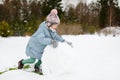 Adorable young girl building a snowman in the backyard. Cute child playing in a snow Royalty Free Stock Photo