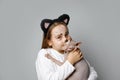 Adorable young girl child painting kitten face cuddling with cat pet on grey studio wall background Royalty Free Stock Photo