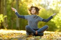 Adorable young girl having fun on beautiful autumn day. Happy child playing in autumn park. Kid gathering yellow fall foliage Royalty Free Stock Photo