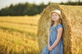 Adorable young girl having fun in a wheat field on a summer day. Child playing at hay bale field during harvest time. Kid enjoying Royalty Free Stock Photo