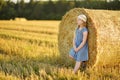 Adorable young girl having fun in a wheat field on a summer day. Child playing at hay bale field during harvest time. Kid enjoying Royalty Free Stock Photo