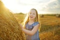 Adorable young girl having fun in a wheat field on a summer day. Child playing at hay bale field during harvest time. Kid enjoying Royalty Free Stock Photo