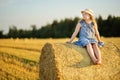 Adorable young girl having fun in a wheat field on a summer day. Child playing at hay bale field during harvest time. Kid enjoying Royalty Free Stock Photo