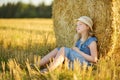 Adorable young girl having fun in a wheat field on a summer day. Child playing at hay bale field during harvest time. Kid enjoying Royalty Free Stock Photo