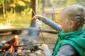 Adorable young girl roasting marshmallows on stick at bonfire. Child having fun at camp fire. Camping with children in fall forest Royalty Free Stock Photo