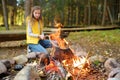 Adorable young girl roasting marshmallows on stick at bonfire. Child having fun at camp fire. Camping with children in fall forest Royalty Free Stock Photo