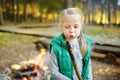 Adorable young girl roasting marshmallows on stick at bonfire. Child having fun at camp fire. Camping with children in fall forest Royalty Free Stock Photo