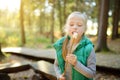 Adorable young girl roasting marshmallows on stick at bonfire. Child having fun at camp fire. Camping with children in fall forest Royalty Free Stock Photo