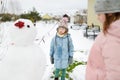 Adorable girls building a snowman in the backyard. Cute children playing in a snow. Winter activities for kids Royalty Free Stock Photo