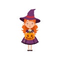 Young red-haired girl witch standing with pumpkin face in her hands and wearing purple dress and hat. Kid character in Royalty Free Stock Photo