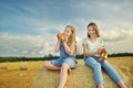 Adorable young sisters eating pretzels in a wheat field on a summer day. Children playing at hay bale field during harvest time. Royalty Free Stock Photo