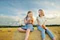 Adorable young sisters eating pretzels in a wheat field on a summer day. Children playing at hay bale field during harvest time. Royalty Free Stock Photo