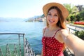 Adorable young woman with hat making selfie photo on Lake Como. Self portrait girl posing in Bellagio, Italy Royalty Free Stock Photo