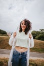 An adorable young woman smiling in a white rain jacket with the hood on her head, putting on her jacket in a rainy day in the