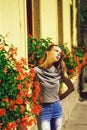 Adorable, young woman standing near blossoming flower pots on windows