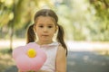 Adorablr little girl holding flower shape balloon outdoors in summer park