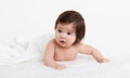 Adorably baby lie on towel in bed, white background. Happy childhood and healthcare concept