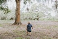 Adorably Happy and Cute Little Caucasian Toddler Baby Boy with Long Blond Hair Laughing, Playing, and Running Outside in Green Nat Royalty Free Stock Photo