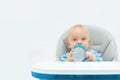 The adored child is sitting in a child`s chair, looking at the camera and holding a bottle of water Royalty Free Stock Photo