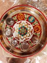 Adorned Indian puja plate containing bowl, a diya and an incense stick stand as well as a shree and a mark of Om.
