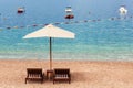 Adriatic sea summer beach. Wooden chairs and umbrella on pebble beach by blue water. Montenegro, Budva riviera Royalty Free Stock Photo