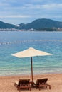 Adriatic sea summer beach. Wooden chairs and umbrella on pebble beach by blue water. Montenegro, Budva riviera Royalty Free Stock Photo