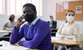 Adult aframerican man in protective mask during lesson in extension school