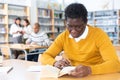 Adult aframerican man reading books and making notes in library