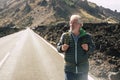 Adult aged senior man walking with backpack in long road at the mountain enjoying the alternative vacation trip and living a Royalty Free Stock Photo