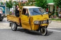 An adult Albanian woman rides in the back of a homemade truck on Shkoder street. Three wheeled