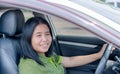 Adult Asia woman with glad positive expression, being satisfied with unforgettable journey by car, sits on driver`s seat, enjoys