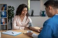 Adult asian man doctor measures pressure of smiling young black female patient in clinic office interior