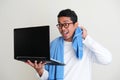 Adult Asian man doing online meeting using laptop while still wearing sleeping clothes and towel around his neck Royalty Free Stock Photo