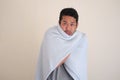 Adult Asian man feeling cold and cover his body using blanket